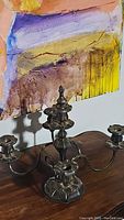 Full view of vintage metal 3-arm candelabra candleholder on wooden surface, showing its shape and design.