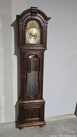 Full view of the vintage grandfather clock showing the wood cabinetry and arched top.