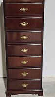 Front view of the seven drawer lingerie chest showing the brass handles and dark wood finish.