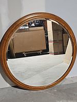 Front view of large round mirror showing wood frame and reflective glass.
