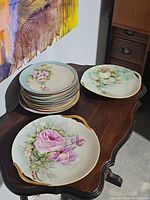 Overview of all dishes including stack of floral plates and two large serving platters on wooden table