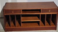 Front view of vintage TV stand showing drawers, open shelf, and vertical compartments.