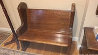 Front and side view of the vintage wooden pew style bench showing the medium brown wood finish and scratches.