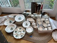 Wide view of the full set of Christmas china including plates, cups, serving pieces all arranged on the floor.