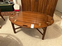 Oval tabletop with both drop leaves raised, showing brass hinges and wood grain
