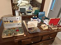 Full dresser top showing multiple open jewelry cases and various loose necklaces and keychain