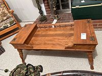 View of the Ethan Allen coffee table with one end open, showing internal storage and hinged wooden ends.