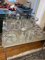Wide view of full collection showing pitchers, vases, serving bowls, butter dishes, and platter on a table