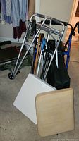Full view of metal walkers, canes clustered together, and two cushions on floor