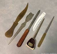 Full view of six assorted vintage letter openers showing variety in design and materials.