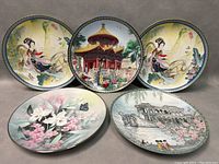 Front view of all five plates showing varied Chinese-themed and floral designs