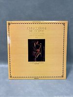 Front cover of the vinyl record album 'Two Giants Together' featuring John Coltrane and Eric Dolphy with photo and titled text on cream background with decorative border.