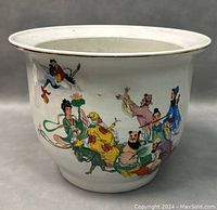 Front angle of the ceramic flower pot showing colorful hand-painted traditional Chinese figures on white ceramic surface.