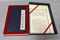 Closed vintage book in dark blue fabric cover with Chinese calligraphy label, housed in fabric-lined box.