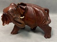 Side angle showing detailed carving on elephant trunk, ears, and legs with visible polished wood grain and slight wear.
