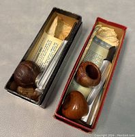 Two tobacco pipes (Spiral Kool and Kirsten) presented in their original boxes with accompanying paperwork, laid side by side.