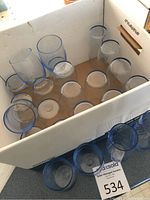 Box containing 11 tall blue glasses and 13 small blue glasses, showing the glazing and size difference.