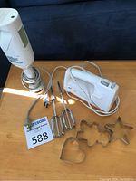 Photo of Black & Decker hand mixer, beaters, electric cords, and three metal cookie cutters on a wooden surface