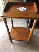 Full front view of the vintage wooden plant stand showing two shelves and turned legs.