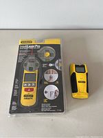 Two Stanley stud finders displayed side-by-side, one in packaging, one loose.