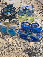Top view of all swimming goggles laid out on granite countertop showing variety of colors and styles.