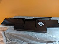 Three floating shelves shown upside down revealing mounting brackets and wood finish, arranged side by side.