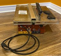 Front view of portable tile cutting saw with power cord and guide on table