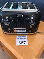 Front view of black Oster 4-slice toaster showing slots, levers, and brand logo.