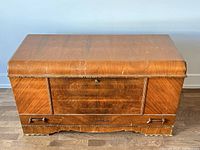 Front view of vintage cedar chest showing wood grain, bottom drawer with wooden handles, and hinged lid top.