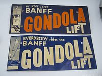 Two rectangular vintage paper souvenir signs from Banff Gondola Lift, one with orange "Gondola" text and the other with off-white "Gondola" text, both showing ski lift cabin and skier images.
