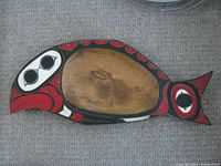 Top side of the feast platter showing detailed Indigenous stylized painting in red, black, and white colors on wood, fish shape with eye and fin motifs.