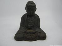 Front view of old iron Buddha statue sitting cross-legged with hands holding bowl