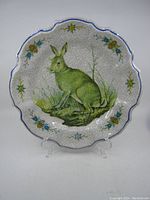 Front view of ceramic wall plate with rabbit design and floral border on scalloped edge