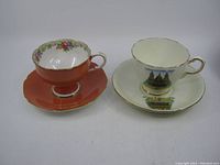 Front view of both teacup and saucer sets showing the Paragon floral design with coral background on the left and Delphine St. Paul's Cathedral design on the right.