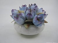 Porcelain flower arrangement with blue and purple crocus flowers on white base.