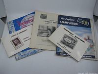 Five vintage stamp albums and booklets laid out showing titles and covers featuring British Empire stamps and John F. Kennedy stamps.