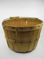 Front view of the wooden splint basket with metal handle and wooden grip, showing the detailed wood grain and dark marks on the slats.