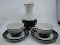 Set of Zsolnay porcelain pieces including vase, teacup and saucer, showing the overall set and matching decorative patterns.