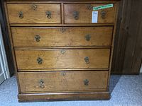 Front view of the antique wooden dresser showing five drawers with metal handles and keyholes.