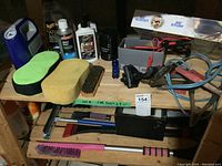 Overview photo showing all car care items including cleaning supplies, oil filter, battery charger and accessories on a wooden shelf