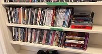 Two shelves filled with approx. 75 DVD cases, arranged horizontally and vertically, showing various titles