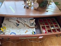 Photo showing various jewelry items spread out including bracelets, earrings, necklaces, and brooches arranged in a drawer with a wooden divided box containing small items