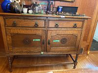 Front view of oak sideboard showing two drawers over two cabinet doors with carved medallions and nailhead trim