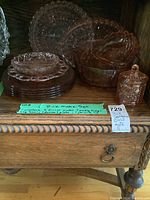 Pink Depression glass set on wooden shelf, including plates, platters, bowls, and covered canister, labeled as Lot 21