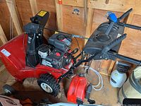 Full view of snow blower with gas can and oil bottle on shed floor