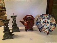 Front view of the entire lot showing the wooden pot, pair of metal candle holders, and large decorative painted platter.