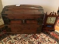 Full view of the antique wooden chest next to the Daneker clock showing approximate scale and condition of both items.