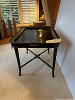 Full view of the black tray on its folding stand showing the raised edges and tray handles.