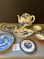 Photo showing full tea set including teapot, small bowls, plates, serving dish, and ceramic trivet all featuring blue and white decoration