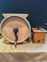 Photo showing front view of wooden butter churn and vintage coffee grinder with crank handle mounted on top